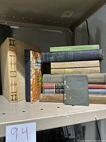 Photo showing a collection of 12 vintage hardcover books arranged on a shelf, including 'The Oregon Trail' and others stacked horizontally and vertically.