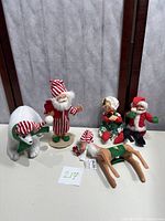 Five vintage Annalee Christmas dolls including Santa, Mrs. Claus, polar bear, and reindeer displayed on floor against wall.