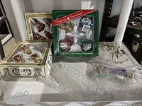 Photo showing three boxed sets of vintage glass ornaments and two clear textured glass icicles in front.