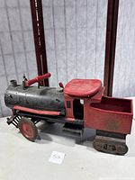 Side view showing the entire ride-on train engine with black boiler, red seat, wheels, and faded Keystone logo.