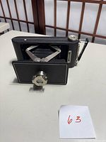 Side view of the Kodak 16mm film enlarger showing folded bellows and textured black body with metal adjustment components.