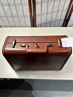 Closed view of the vintage Samsonite small leather suitcase showing the brown exterior, handle, metal clasps, and combination lock.