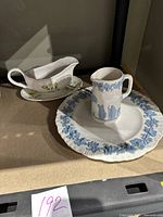 Blue on white Wedgwood creamer jug with classical figure relief and rimmed plate with blue grapevine and leaf border.