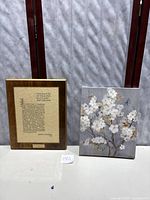 Wide shot of the wooden plaque and canvas blossom artwork displayed side by side on a table.
