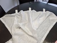 White crinkle texture curtain panel arranged on black table showing tab tops and fabric texture