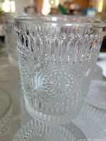 Close-up of one embossed glass showing detailed circular and vertical line pattern.