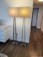 Two IKEA Klabb floor lamps standing side by side, shades lit, showing overall appearance and size.