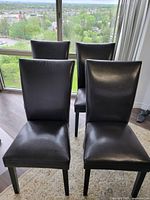 Front angle showing all four chairs arranged on a rug in front of a window.