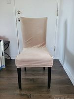 Front view of taupe stretch velvet chair cover fitted onto dining chair.