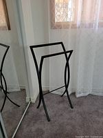 Side angled view showing the black metal towel/blanket rack with curved legs and two parallel bars.
