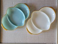 Both vintage divided relish dishes, one blue and one white, showing overall shape and gold-tone beaded edging.