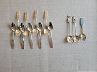 Overview of 12 Christmas souvenir spoons showing varied handles and bowl shapes, including plain to detailed decorations.