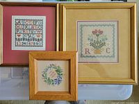 Three framed cross-stitch pieces arranged together showing overall lot