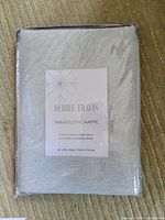 Photo of sealed packaged Debbie Travis tablecloth with label showing 97% cotton, 3% other fibers, 60 by 84 inches size.