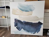 Front view of the abstract canvas artwork showing brushstrokes in blue, beige, and cream colors.