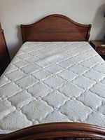 Front view of mahogany headboard and mattress surface showing quilted floral pattern and texture.