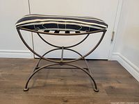 Side view of metal bench with navy cushion and neo-classical curved leg design.