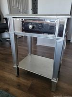 Front and right side view of the mirrored side table showing drawer and shelf
