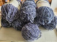 Eight balls of navy blue Bernat Velvet yarn stacked with one ball partially unravelled.