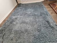 Photo of full navy blue short shaggy rug showing wear spots and pile texture on floor.
