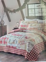 Quilt displayed on bed with Christmas-themed patchwork design of reindeer and wreaths in red and white colors.
