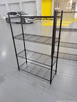 Single metal shelving unit with four wire shelves and bronze-toned finish viewed from angle on warehouse floor.