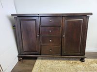 Front view of dark stained wood sideboard showing two doors and four drawers.