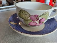 Side view of the white porcelain cafe au lait cup and saucer with botanical plum and butterfly design
