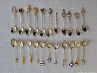 Full view of 22 souvenir spoons showing variety in handle styles and emblems