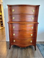 Front view showing five drawers with brass handles and curved front design.