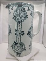 Front view of the vintage stoneware jug showing dark green rose pattern on white background with handle on the right.