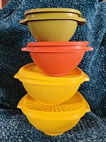 Four stacked vintage Tupperware containers in gold, orange, and yellow-green colors