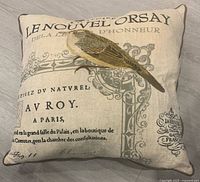 Front view of beige square pillow with bird illustration and French text design showing vintage style and neutral colors.