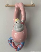 Close-up photo showing pink polka dot monkey ballerina with wooden hanger and rope