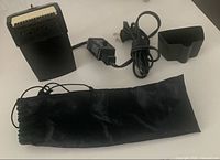 Garment steamer attachments, power cord, and black carrying pouch laid out on surface