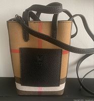 Front view of the small plaid crossbody bag with black front pocket and adjustable strap