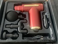 Red massage gun and its four interchangeable heads arranged in plastic packaging insert.