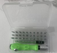 Photo showing open case with green-handled precision screwdriver and 31 assorted bits arranged in two rows inside a clear plastic compact case.