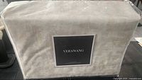 Front view of packed Vera Wang flat sheet in protective clear plastic with branded label.