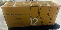 Box with 12 glasses marked as 370 ml, showing brand Gluckstein Home Reception, with graphic of wine glasses on the front.