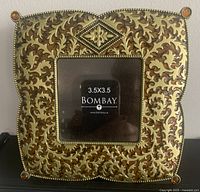 Front view of ornate Bombay Company photo frame showing detailed gold and bronze embellishments, and 3.5 x 3.5 inch photo opening.