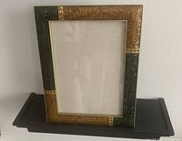 Front view of boxed Bombay Company embellished photo frame against a light gray wall and placed on a dark wooden shelf.