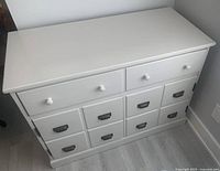 Front view of white wood TV stand with two upper drawers and six lower drawers.