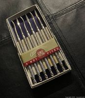 Set of six H.M. Quackenbush nut picks displayed in original box with label