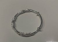 Front angle view of the shiny silver floral bracelet showing detailed floral embellishments and the polished finish.