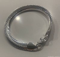 Close-up image showing the polished silver snake chain with lobster claw clasp and purity stamp.
