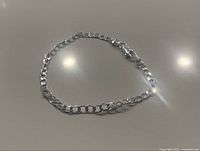 Sterling silver flat design bracelet laid out in a slight curve showcasing the flat rectangular links with lobster claw clasp.
