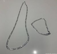 Sterling silver bracelet and necklace laid side by side showing chain link style and clasp detail.