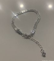 Full view of lightweight sterling silver chain bracelet laid flat showing lobster claw clasp and extender chain with heart-shaped charm