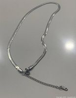 Close-up of sterling silver flat snake chain necklace showing lobster clasp and extender chain with tag marked .925.